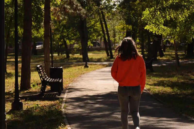 Woman walking along a tree-lined park path