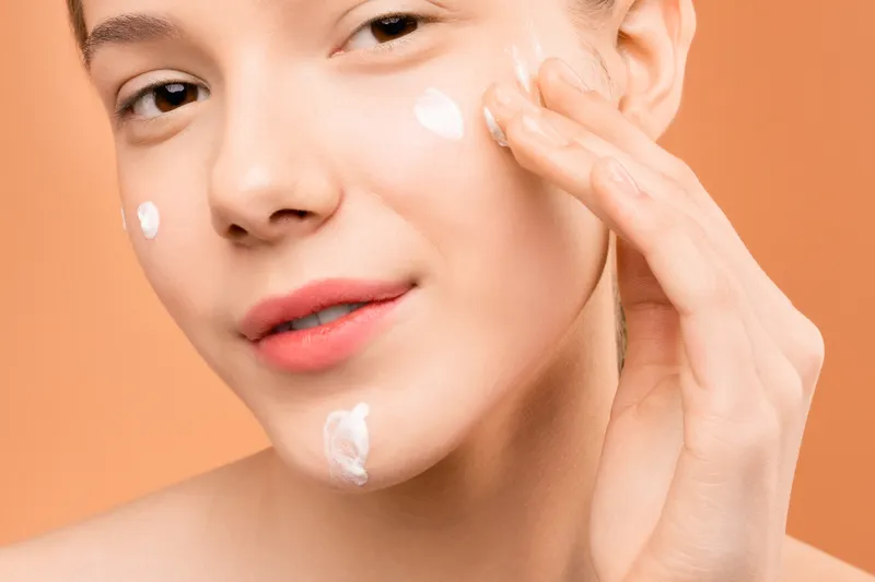 Woman gently applying moisturiser to her cheek