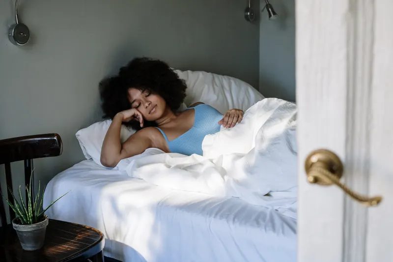 Woman resting in a bright, tidy bedroom
