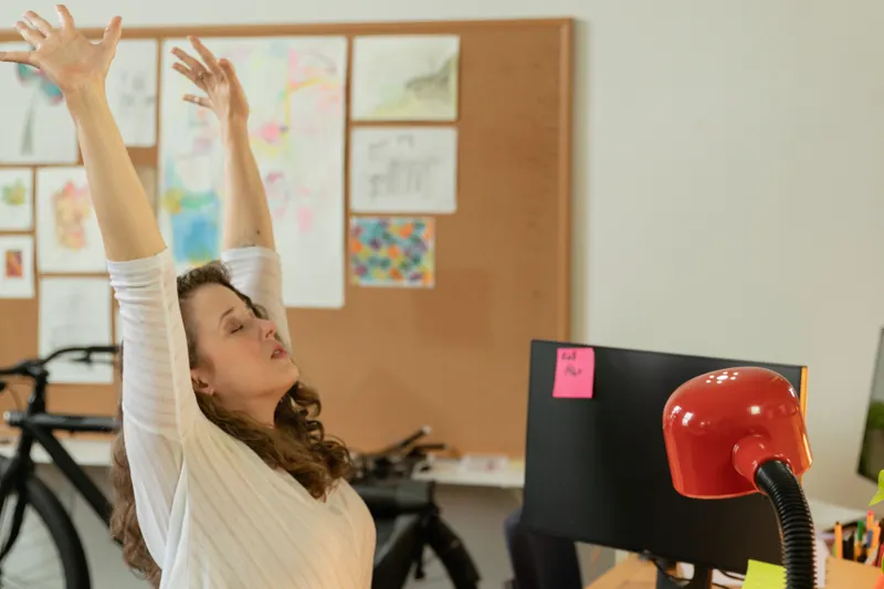 Woman stretching her arms while sitting at a desk
